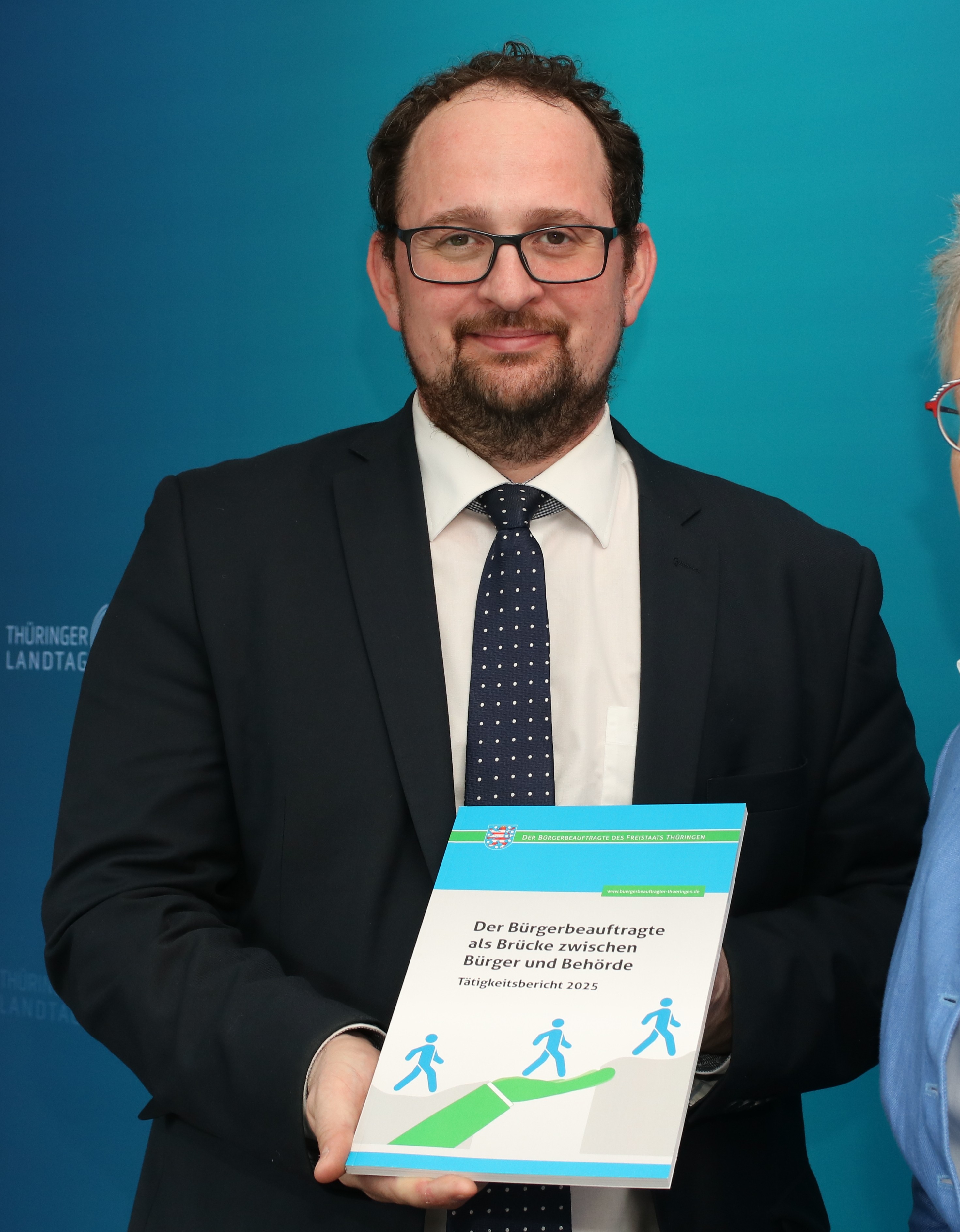 der Landtagspräsident hält den Jahresbericht vor sich in der Hand 