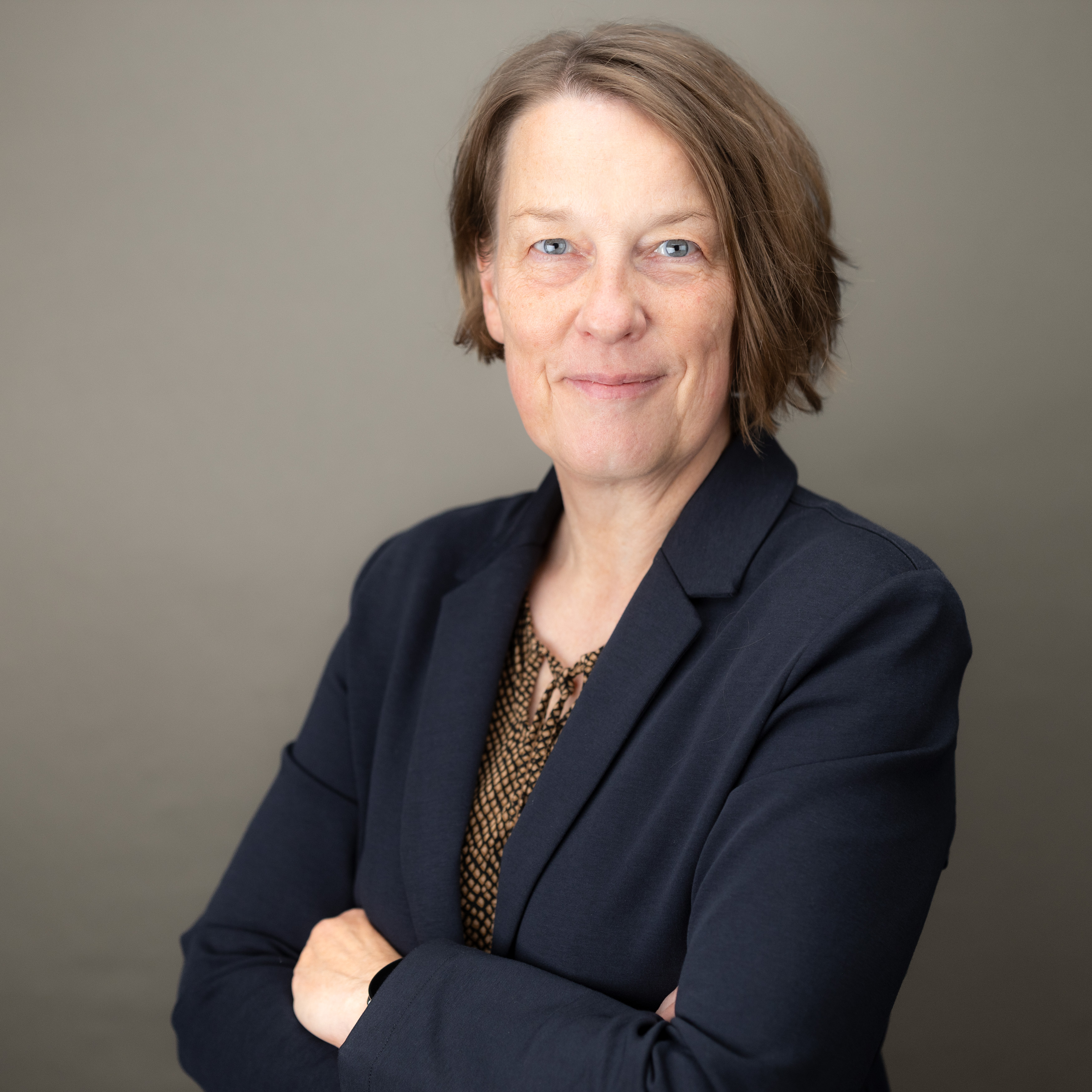 Frau Democh im Profil mit verschränkten Armen, lächelnd 